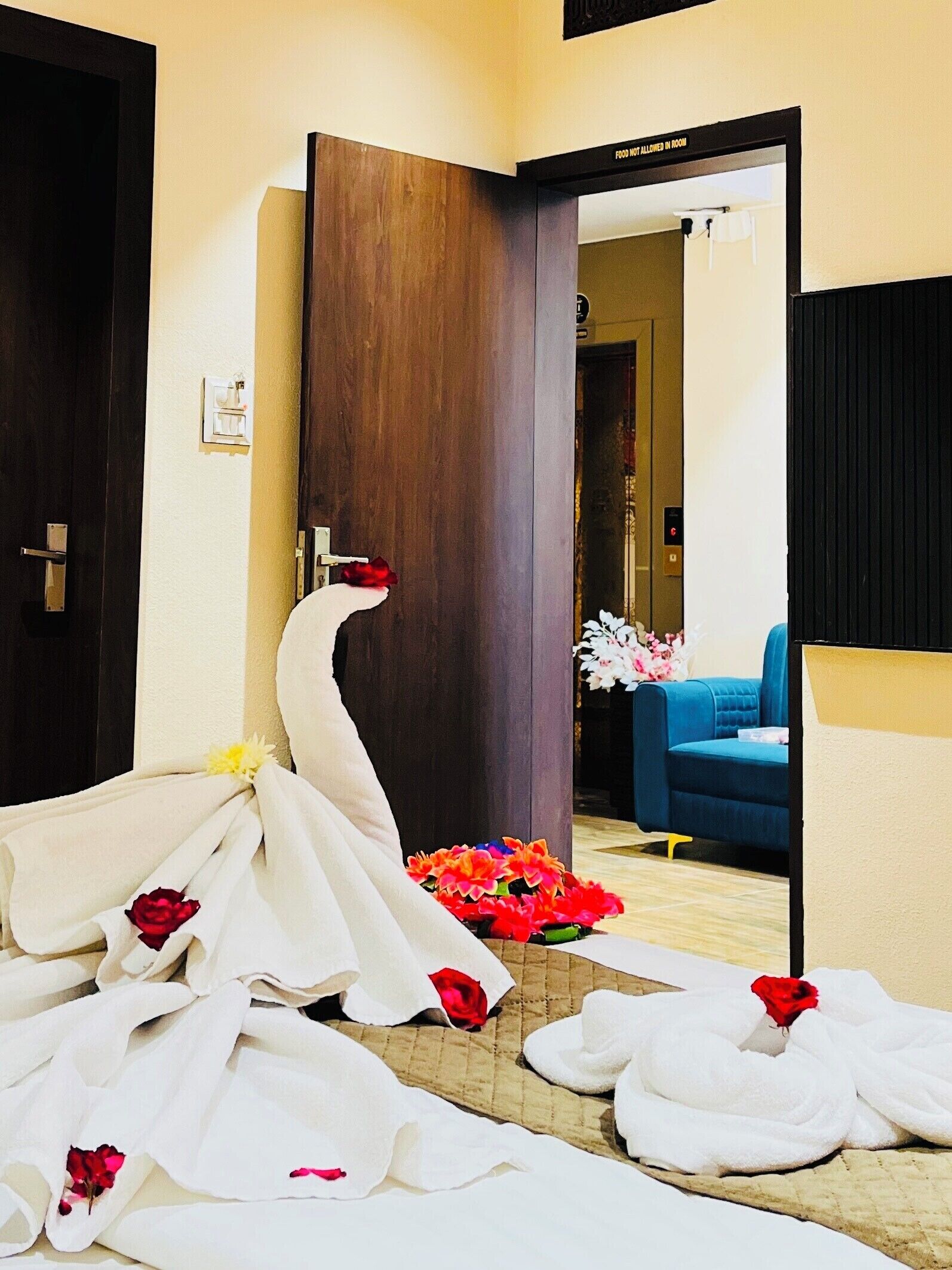 A hotel room with a large mirror, a wooden door, and a blue chair.