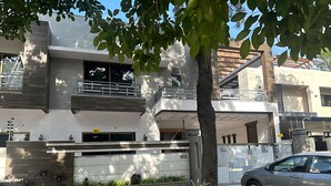 A modern two-story house with a balcony, a tree in the front yard, and a parked car. - Prime View Guest House (Islamabad)