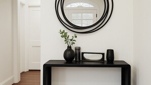 A black console table with a mirror, a vase with green plants, a candle, and a small rectangular object. - <10mins 4rm Downtown, Early check-in, Pets welcome, With pool table (Atlanta)