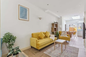 A living room with a yellow sofa, a small table, and a plant. - Charming Windsor Cottage| Castle Views By Tempstay (Windsor)