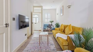 Un salon avec un canapé, un téléviseur et un tapis à motifs.