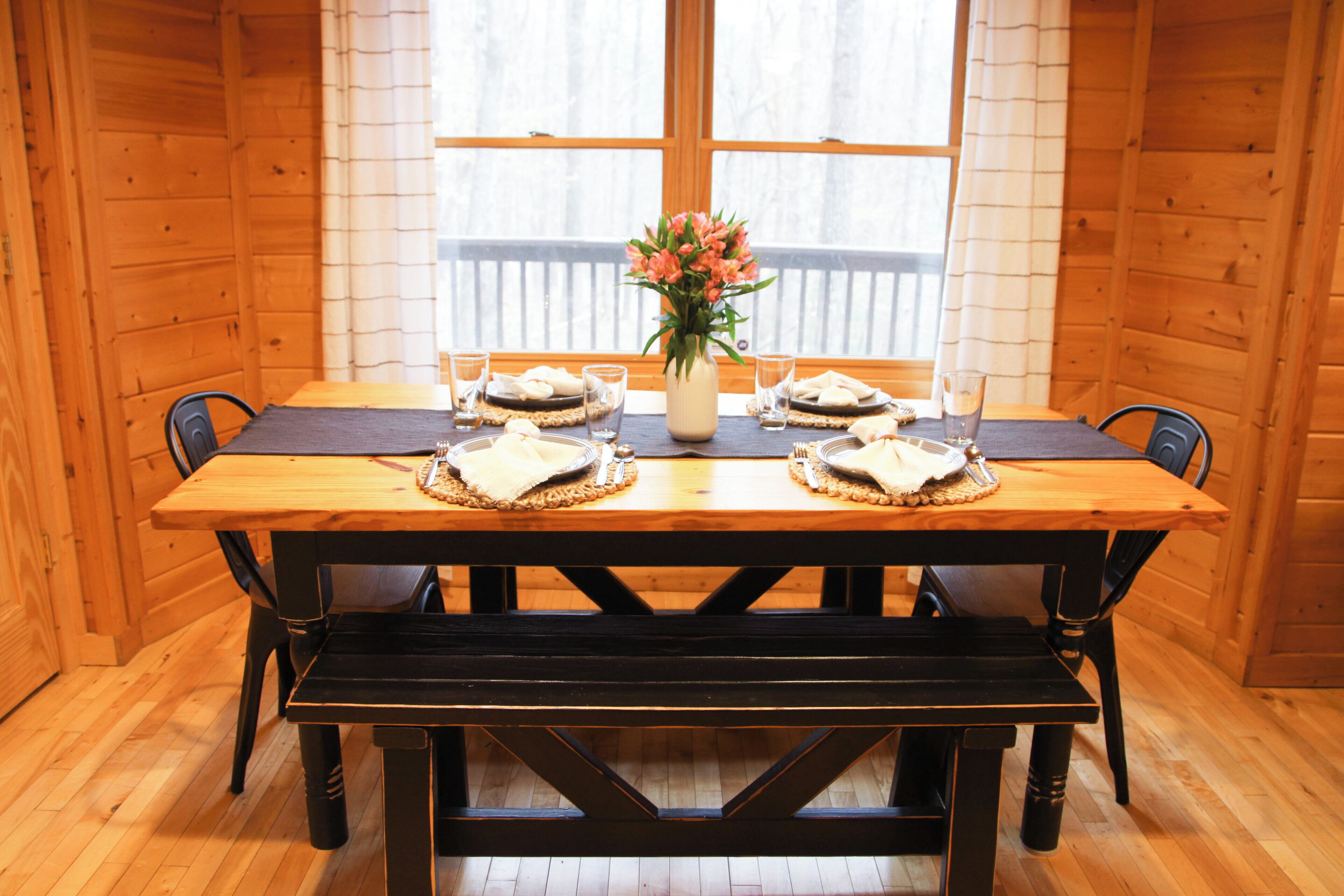 A wooden dining table with a vase of flowers, two plates with food, and two glasses of water.