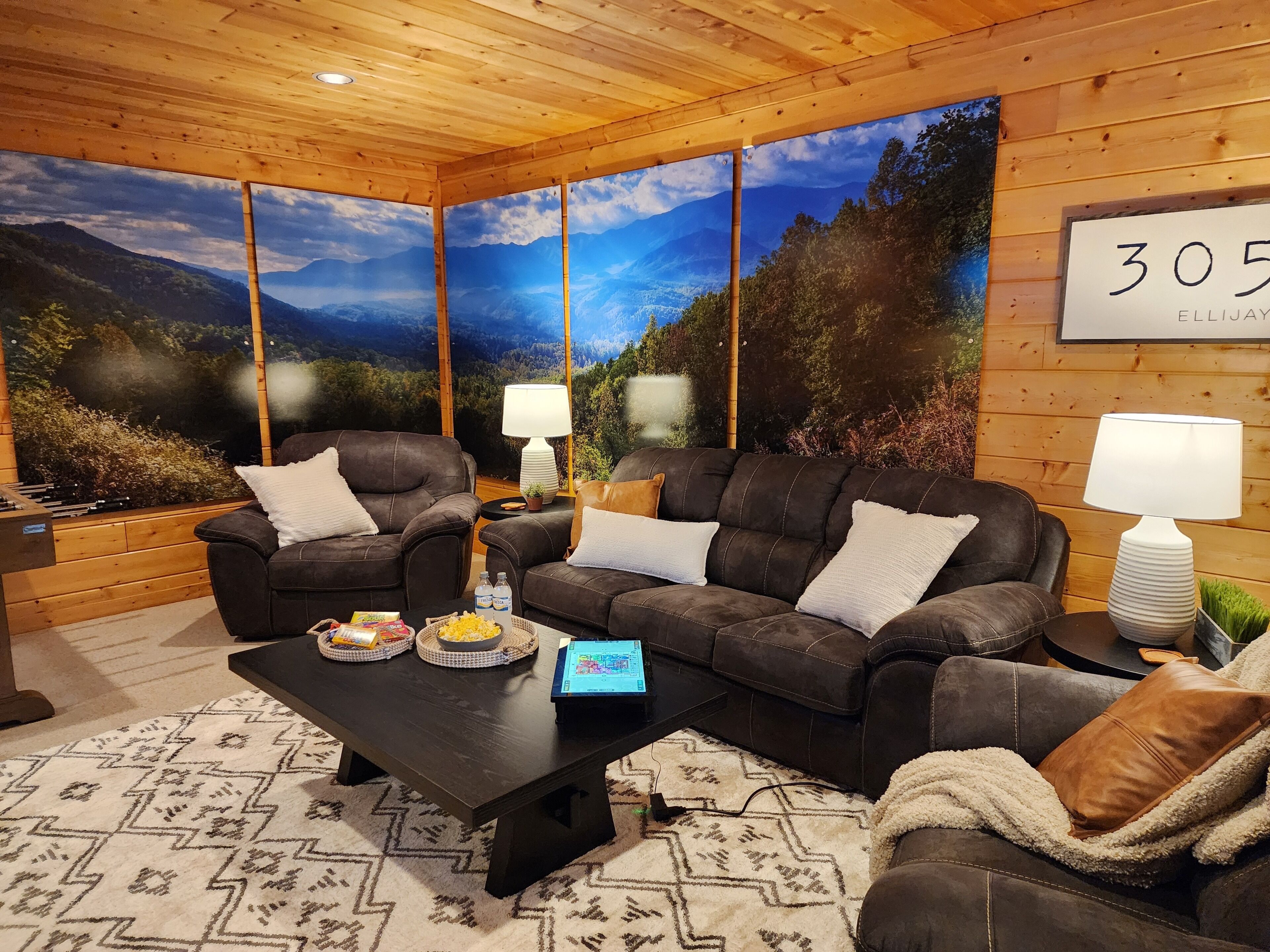 A cozy room with a large window, a sofa set, a coffee table, and a lamp.