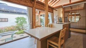 A modern kitchen with wooden beams, a large island, and a view of the garden.