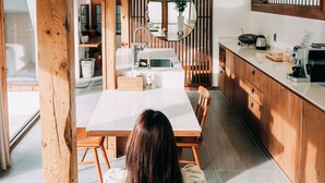 A modern kitchen with wooden beams, a dining table, and a person in a white dress.