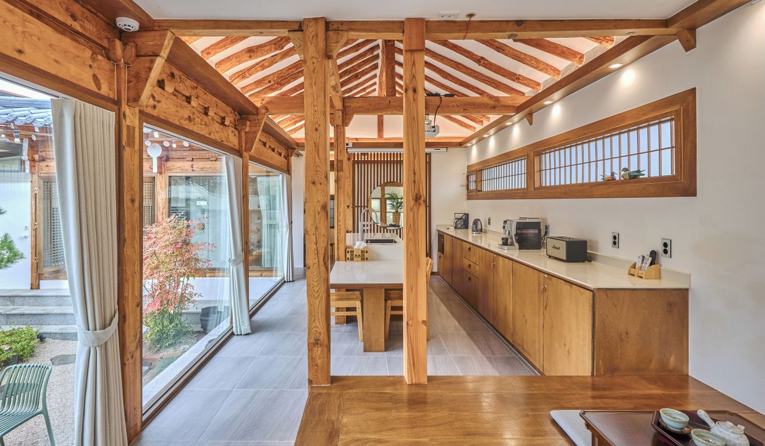 Una cocina moderna con vigas de madera, un ventanal grande y un área de comedor.