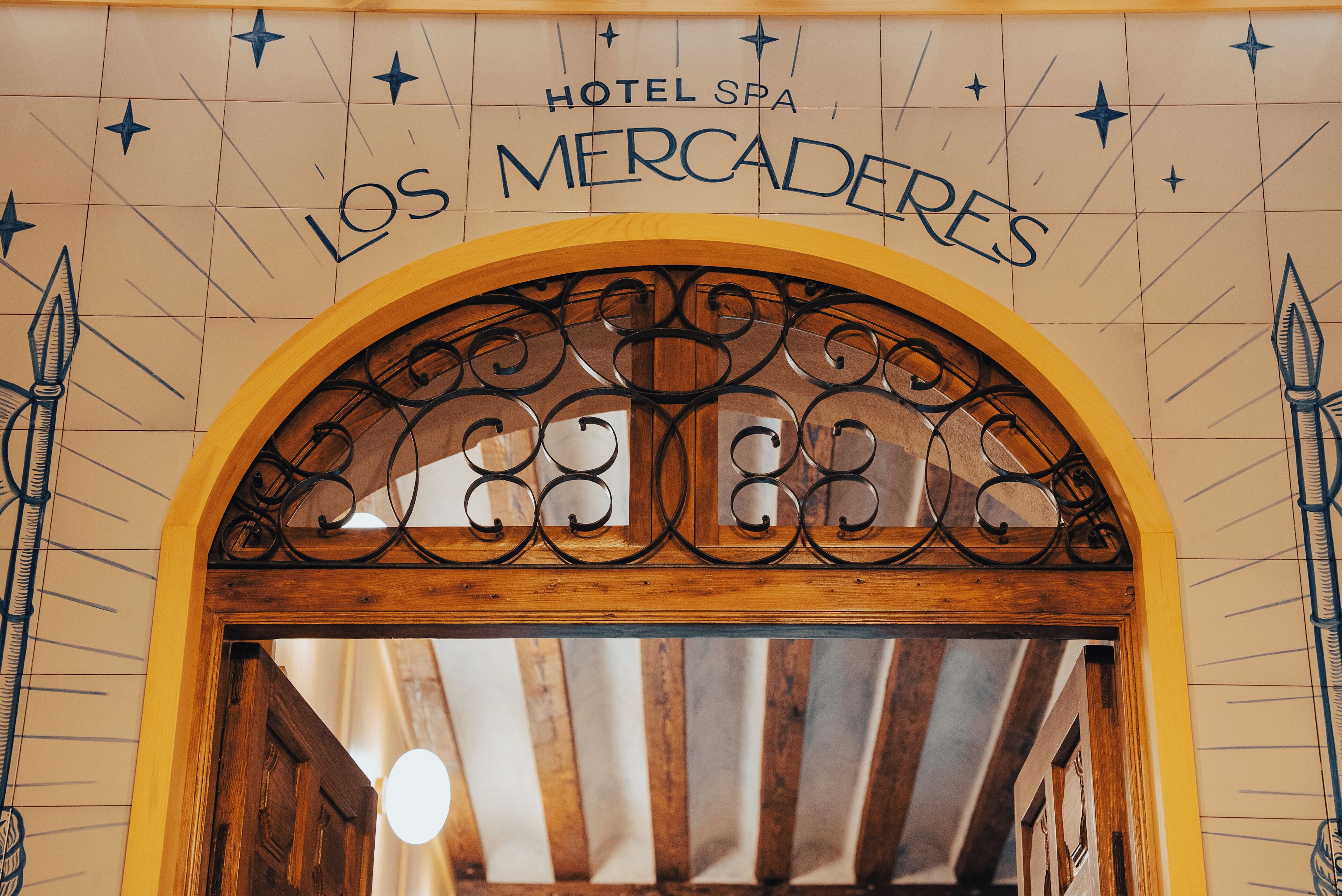 Una entrada arqueada con el texto 'HOTEL SPA LOS MERCADERES' en la parte superior.