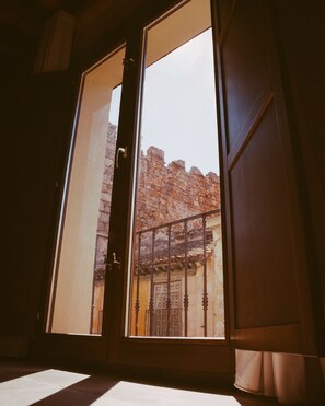 A room with a sliding door leading to an outdoor area with a stone wall and a metal gate.