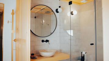 Une salle de bain moderne avec une douche à parois de verre, un miroir rond et un meuble-lavabo en bois doté d’un vasque.