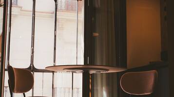 A room with a round table and two chairs, a window with metal bars, and a hanging light fixture.