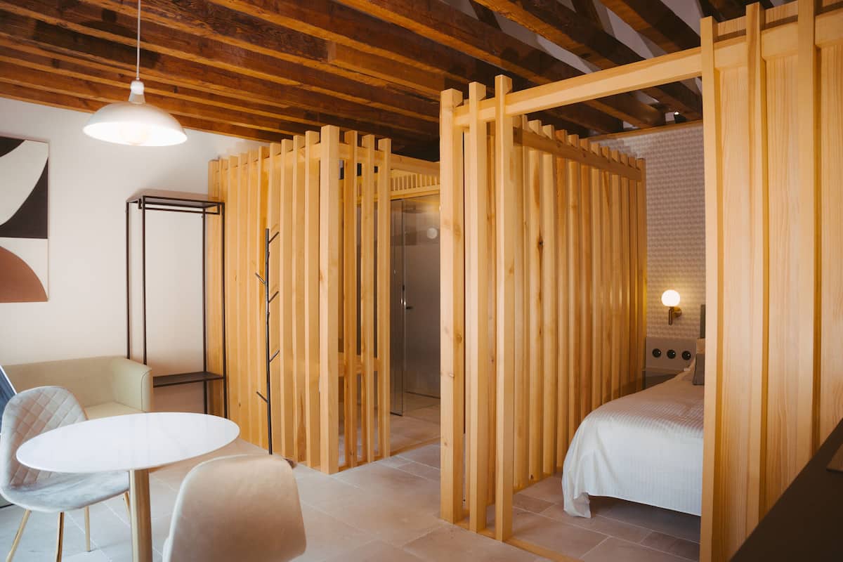 A modern room with a wooden partition, a bed, a round table, and a chair.