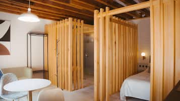 Una habitación moderna con un separador de madera, una cama, una mesa redonda y una silla.