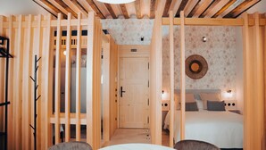 A room with a wooden partition, a bed with patterned bedding, and a round wall decoration. - Los Mercaderes - Hotel & Spa (Talavera de la Reina)