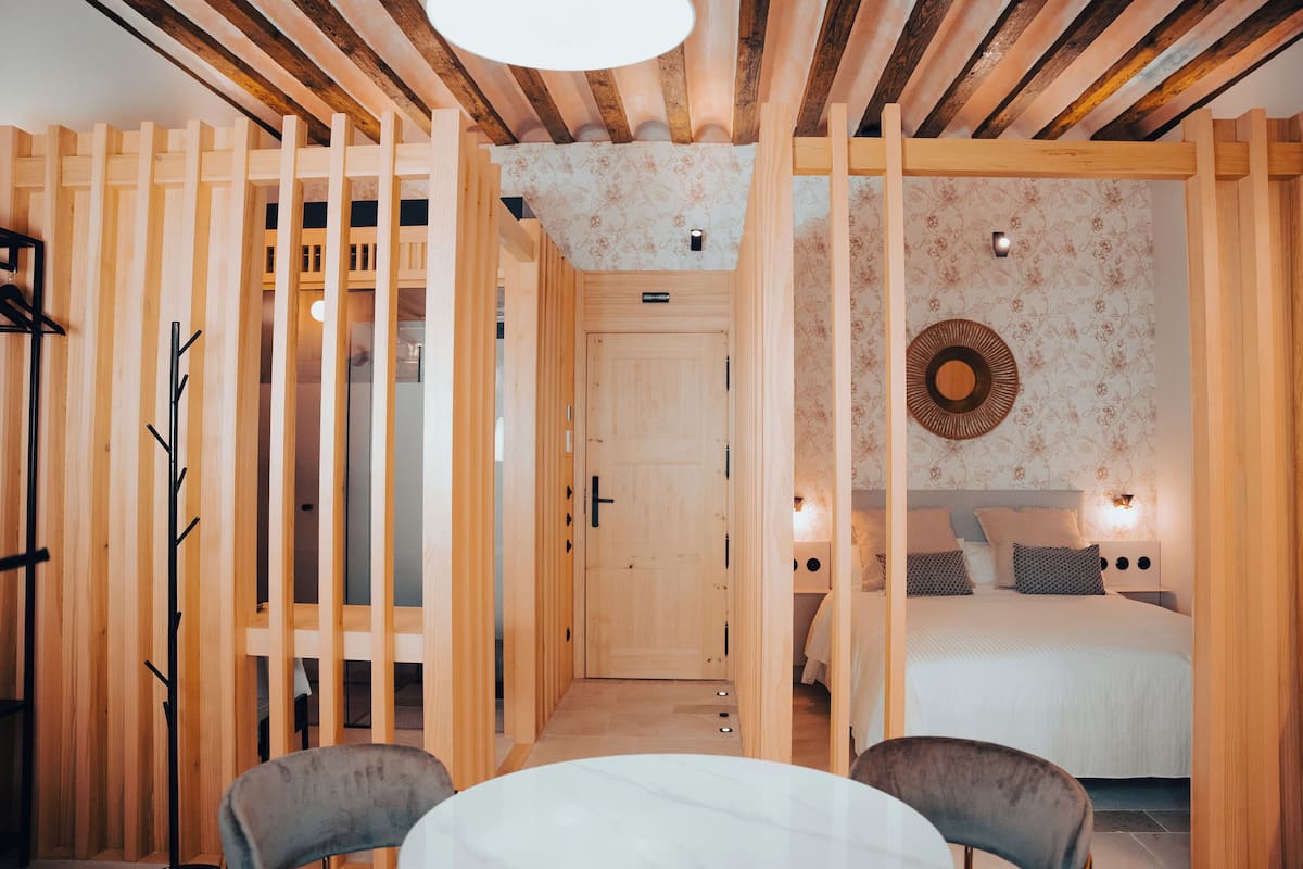A room with a wooden partition, a bed with patterned bedding, and a round wall decoration.