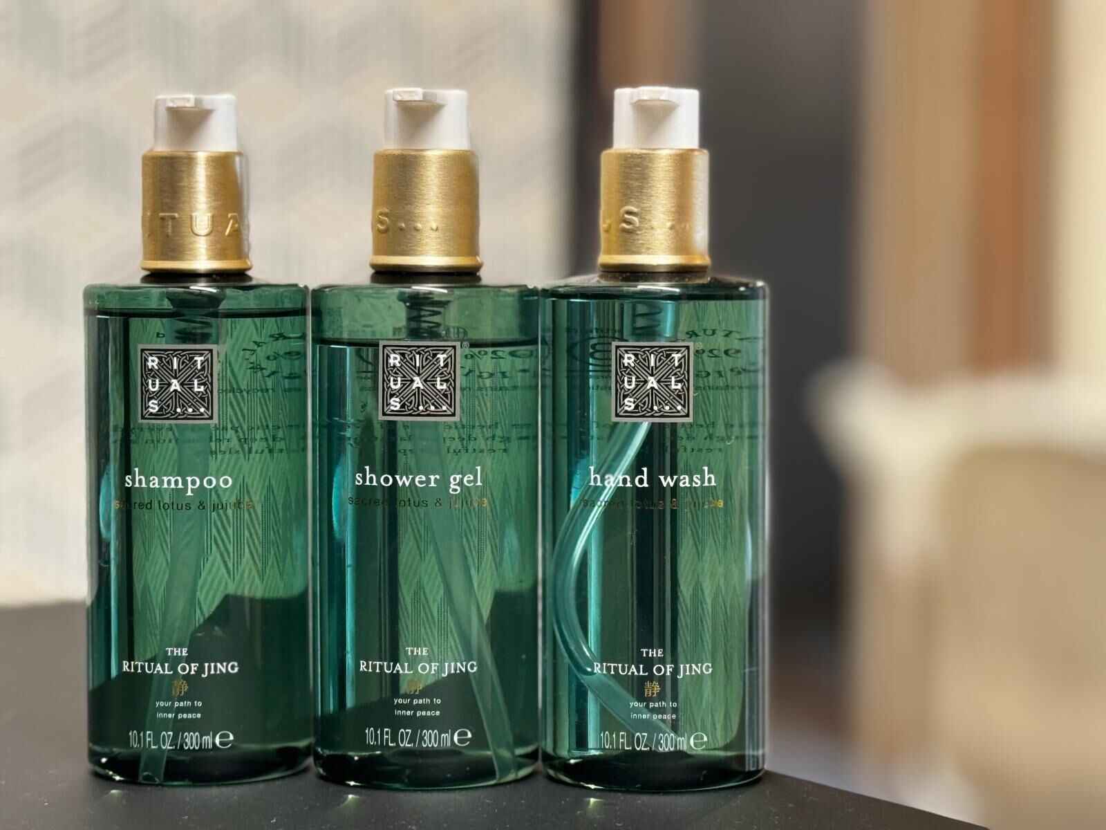 Tres botellas de productos The Ritual of Jing: champú, gel de ducha y jabón de manos.