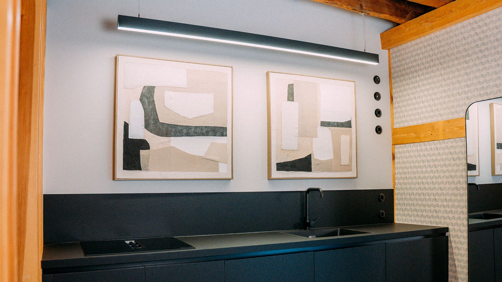 Cuina moderna amb dos quadres abstractes, un vàter integrat i un salvasalses amb dibuixos.