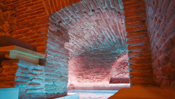 An arched brick structure with a wooden beam and a white platform. - Los Mercaderes - Hotel & Spa (Talavera de la Reina)