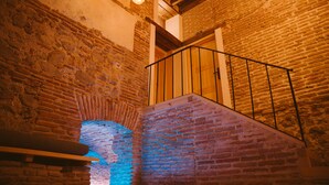 A staircase with a brick wall and wooden beams, leading to a higher floor. - Los Mercaderes - Hotel & Spa (Talavera de la Reina)