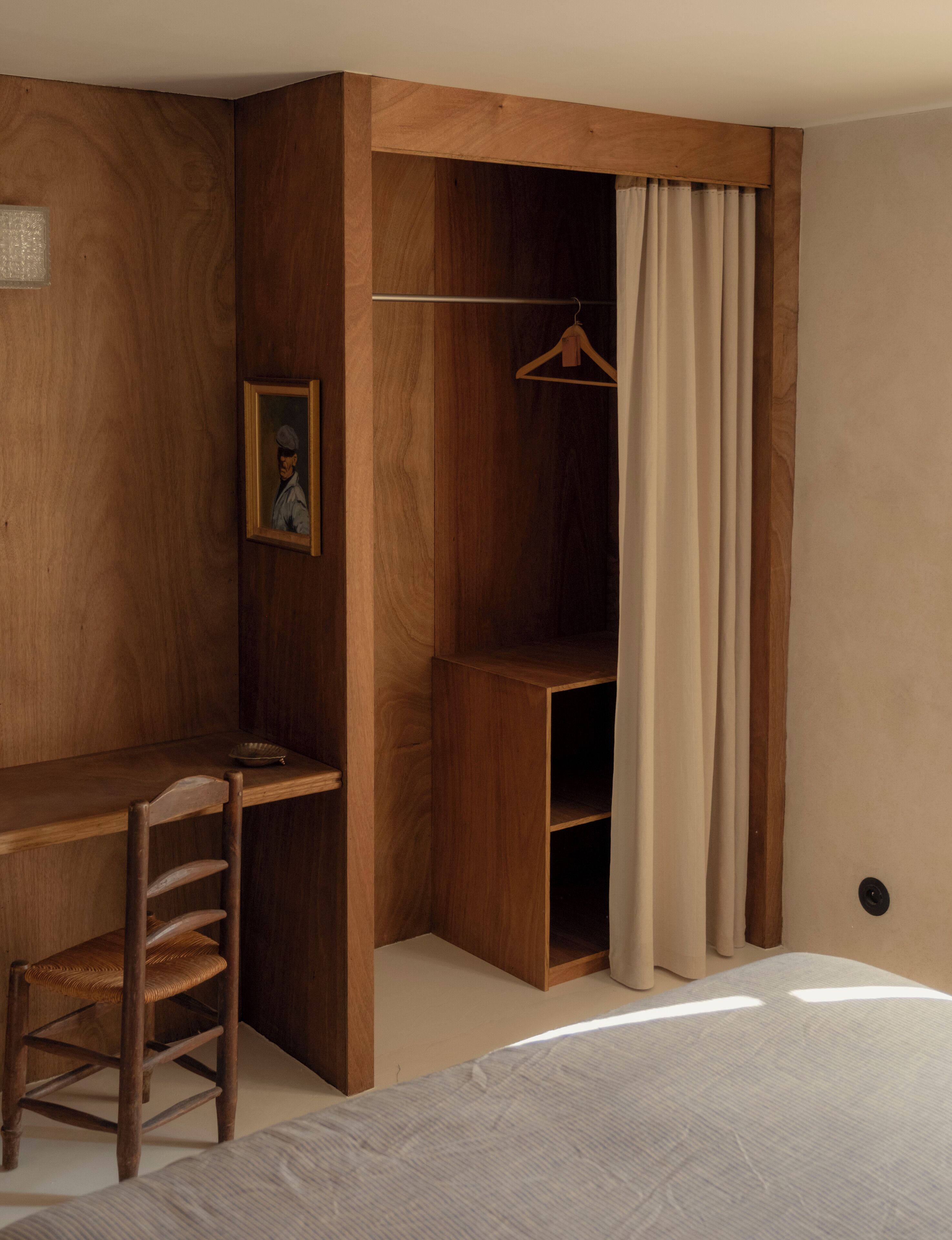 Une chambre avec un bureau en bois, une chaise, un porte-manteau mural et un lit.