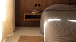 A bedroom with a wooden headboard, a bedside table with a glass of water, a book, and a wall-mounted artwork.
