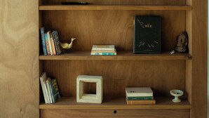 A wooden TV stand with a flat-screen TV, books, decorative items, and a small boat model.