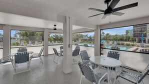 A spacious balcony with a pool view, ceiling fans, and outdoor seating. - SUMMER/FALL DISCOUNT!!!  2B/2B Fairview Isles 123 Condo, Walk to Beach, Heated Pool! (Fort Myers Beach)
