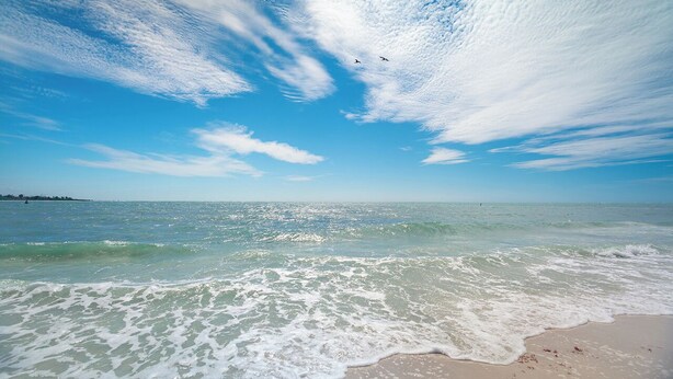 A beach with waves, a clear sky, and distant land. - SUMMER/FALL DISCOUNT!!!  2B/2B Fairview Isles 123 Condo, Walk to Beach, Heated Pool! (Fort Myers Beach)