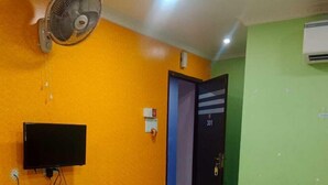 A hotel room with a bed, a TV mounted on the wall, a fan, and an air conditioning unit. - hotel shanavi Tower (Barasat)