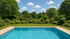 A rectangular swimming pool with clear blue water, surrounded by a well-maintained lawn and dense greenery. - Playotel Grande Rau (Indore)