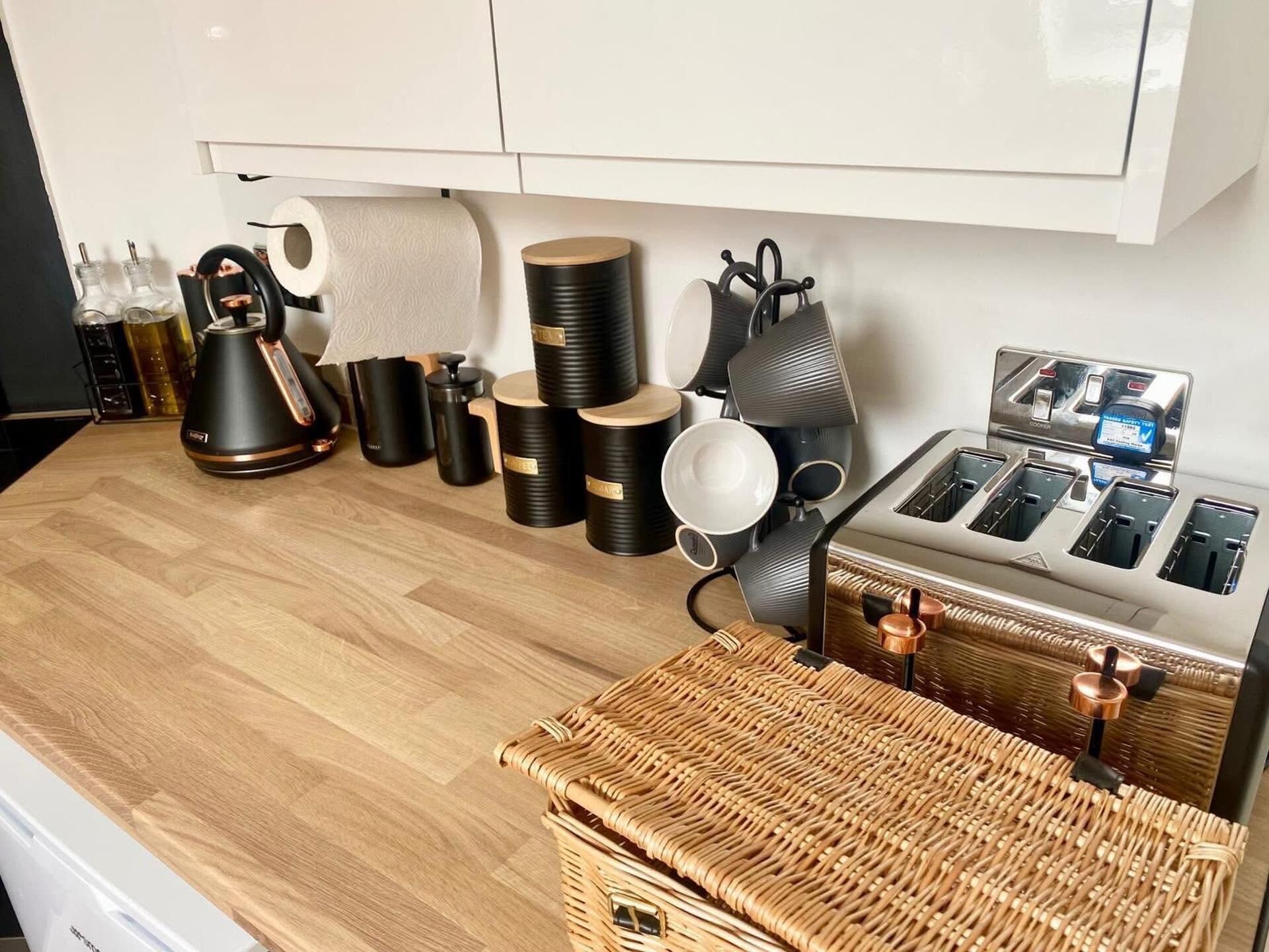 A kitchen with a coffee maker, tea kettle, and various containers.