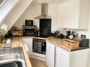 A compact kitchen with a built-in oven, a coffee machine, and a toaster. - Central Tenby 3 Bed Apt Sleeps 6 to 8 Dog Friendly (Tenby)