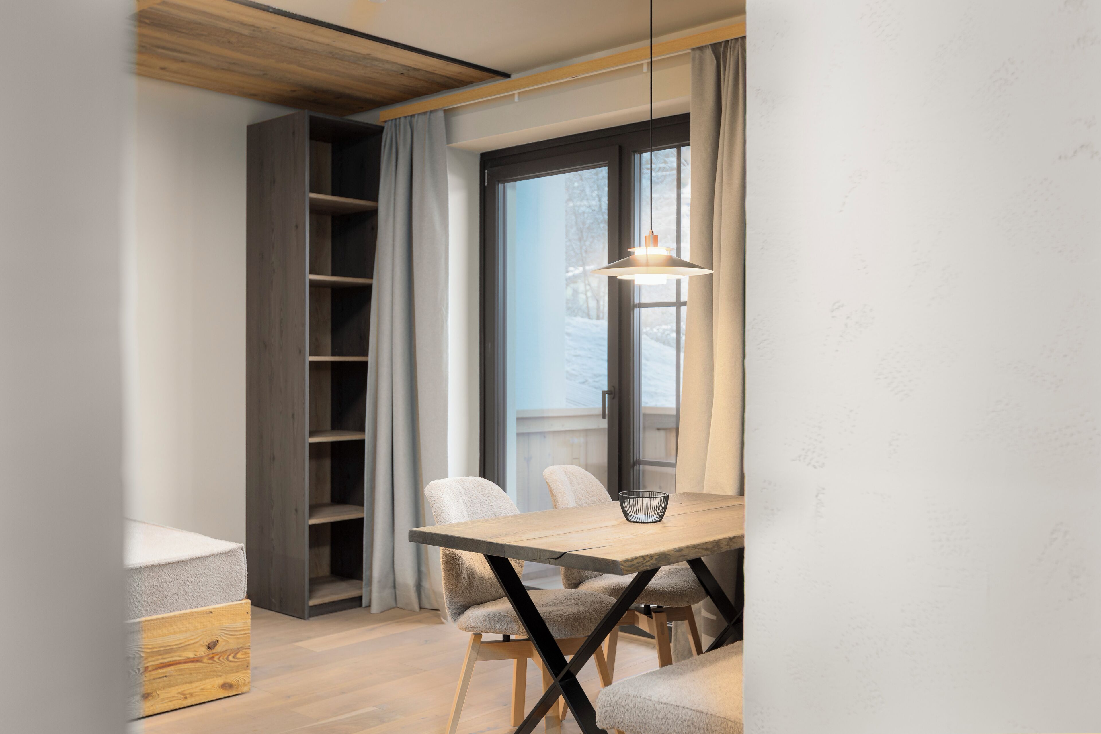 A modern dining area with a wooden table, chairs, and a hanging light fixture.