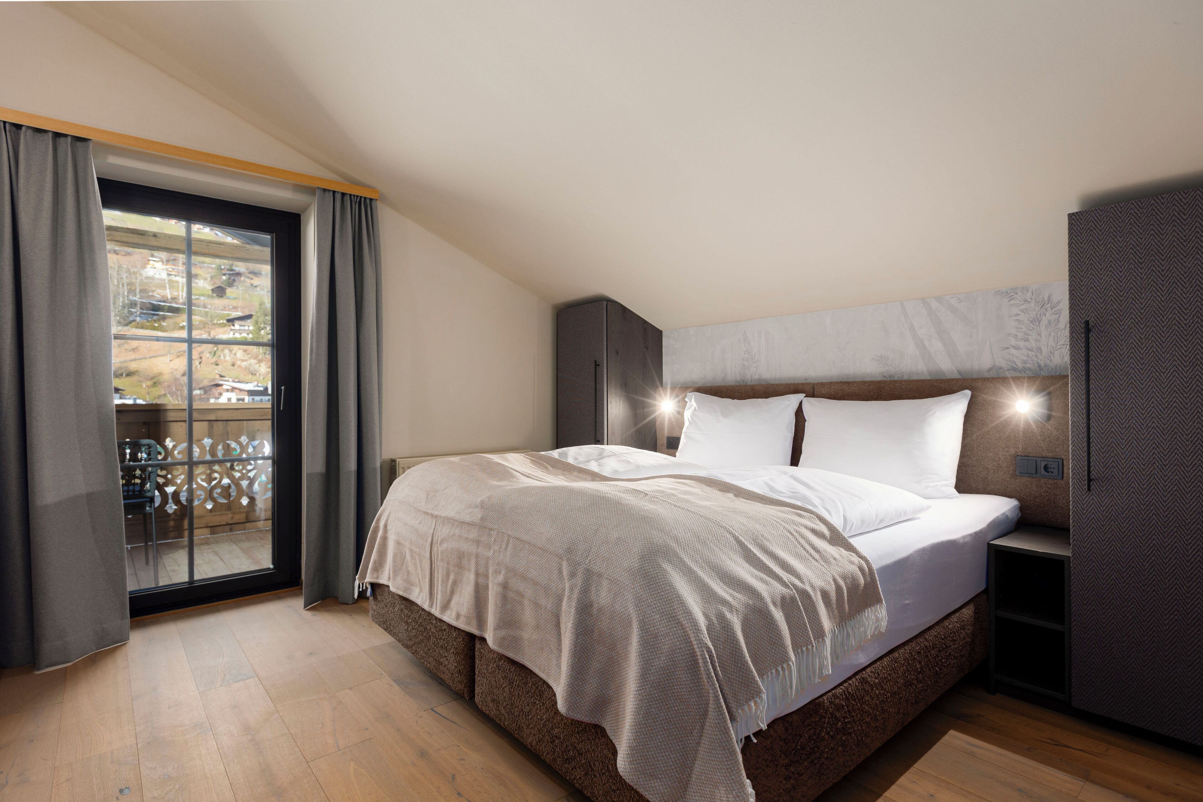 A bedroom with a large bed, a sliding glass door to a balcony, and a built-in wardrobe.