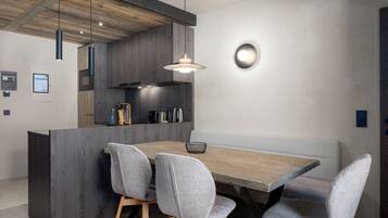 Een moderne eetruimte met een houten tafel, gestoffeerde grijze stoelen en een inbouwwerkbank.