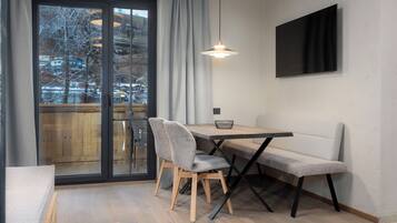 A modern dining area with a wooden table, two chairs, a bench, and a hanging light fixture.
