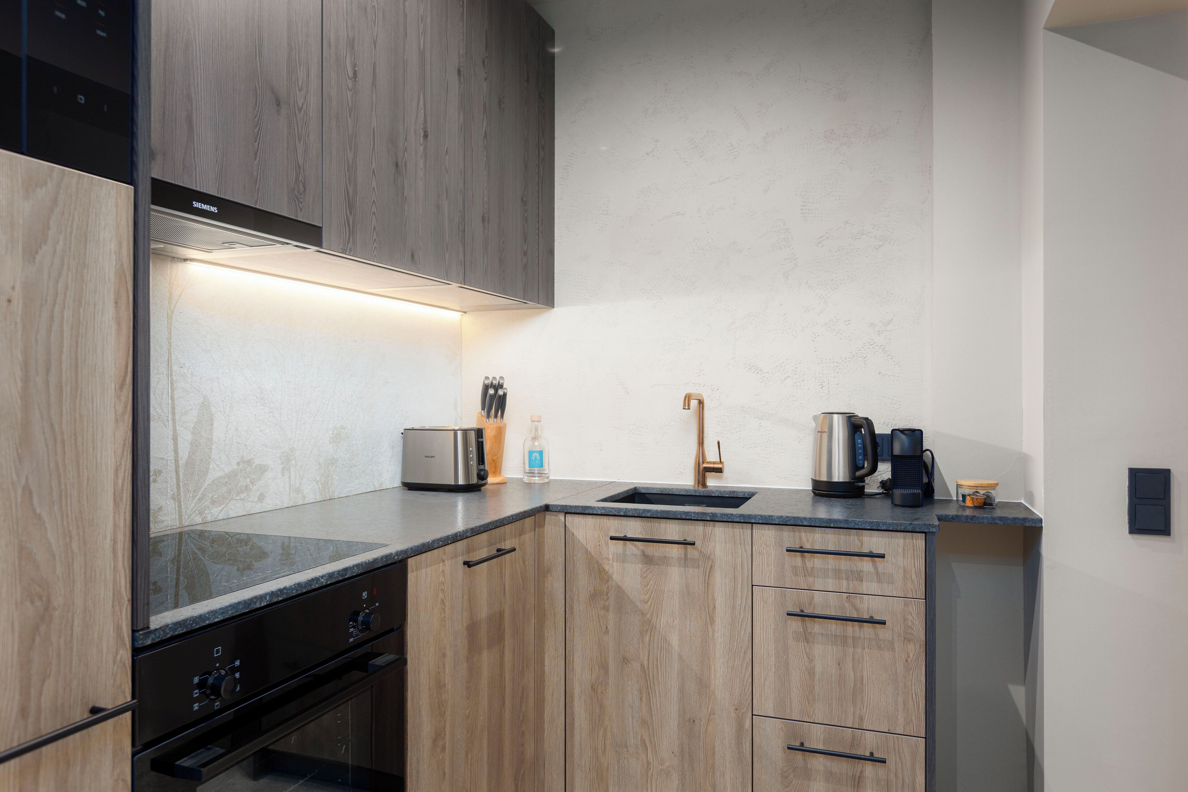 Een moderne keuken met houten kastjes, een roestvrijstalen broodrooster, een koffiezetapparaat en een spoelbak.