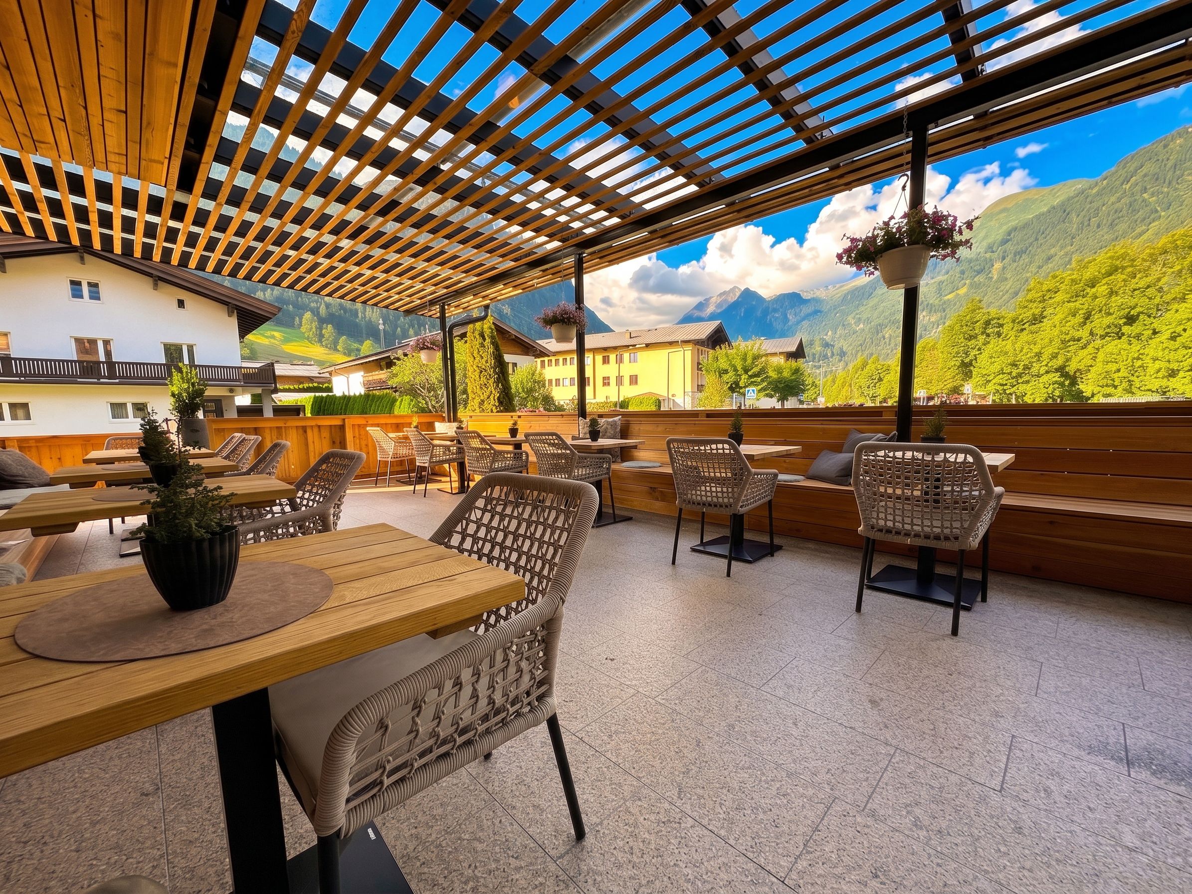 Un espace extérieur aménagé avec des tables et des chaises en bois, offrant une vue sur un paysage montagneux.
