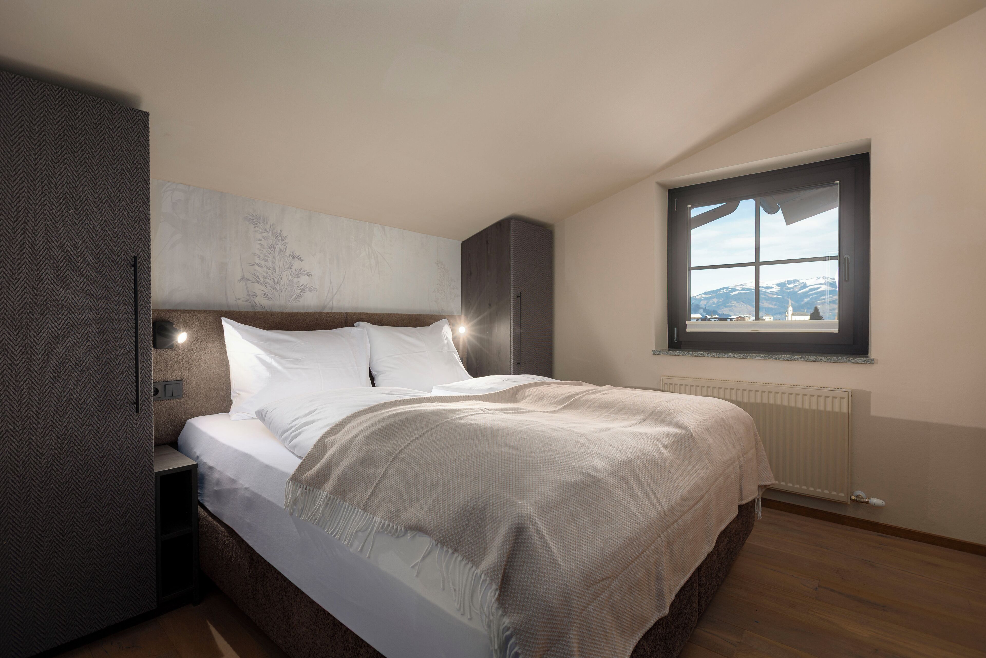 Une chambre moderne avec un grand lit, une table de chevet, une armoire intégrée, une fenêtre avec vue et un radiateur.