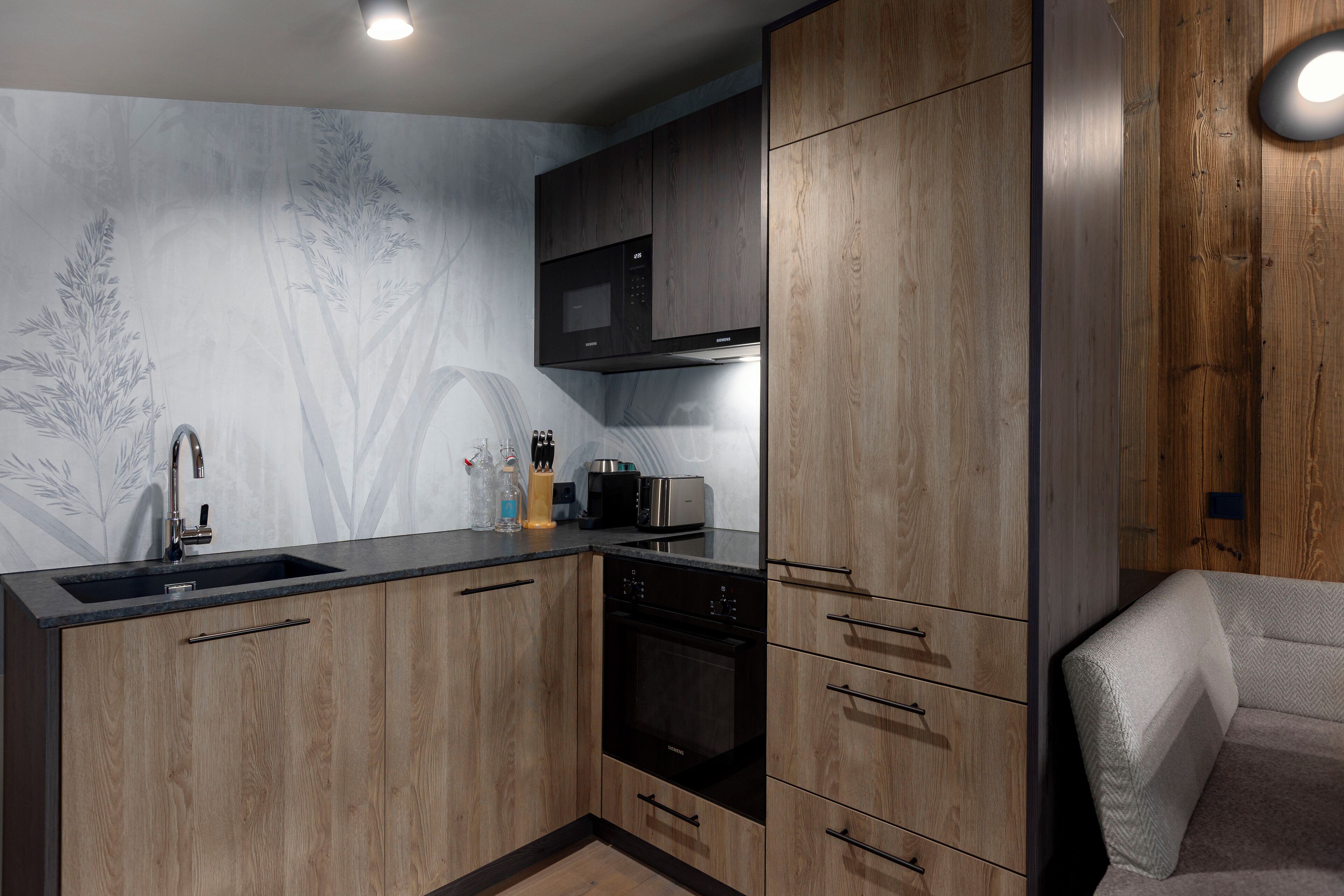 Una cocina moderna con armarios de madera, microondas integrado y un lavamanos de acero inoxidable.