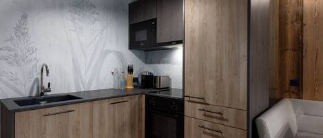 Una cocina moderna con armarios de madera, microondas integrado y un lavamanos de acero inoxidable.