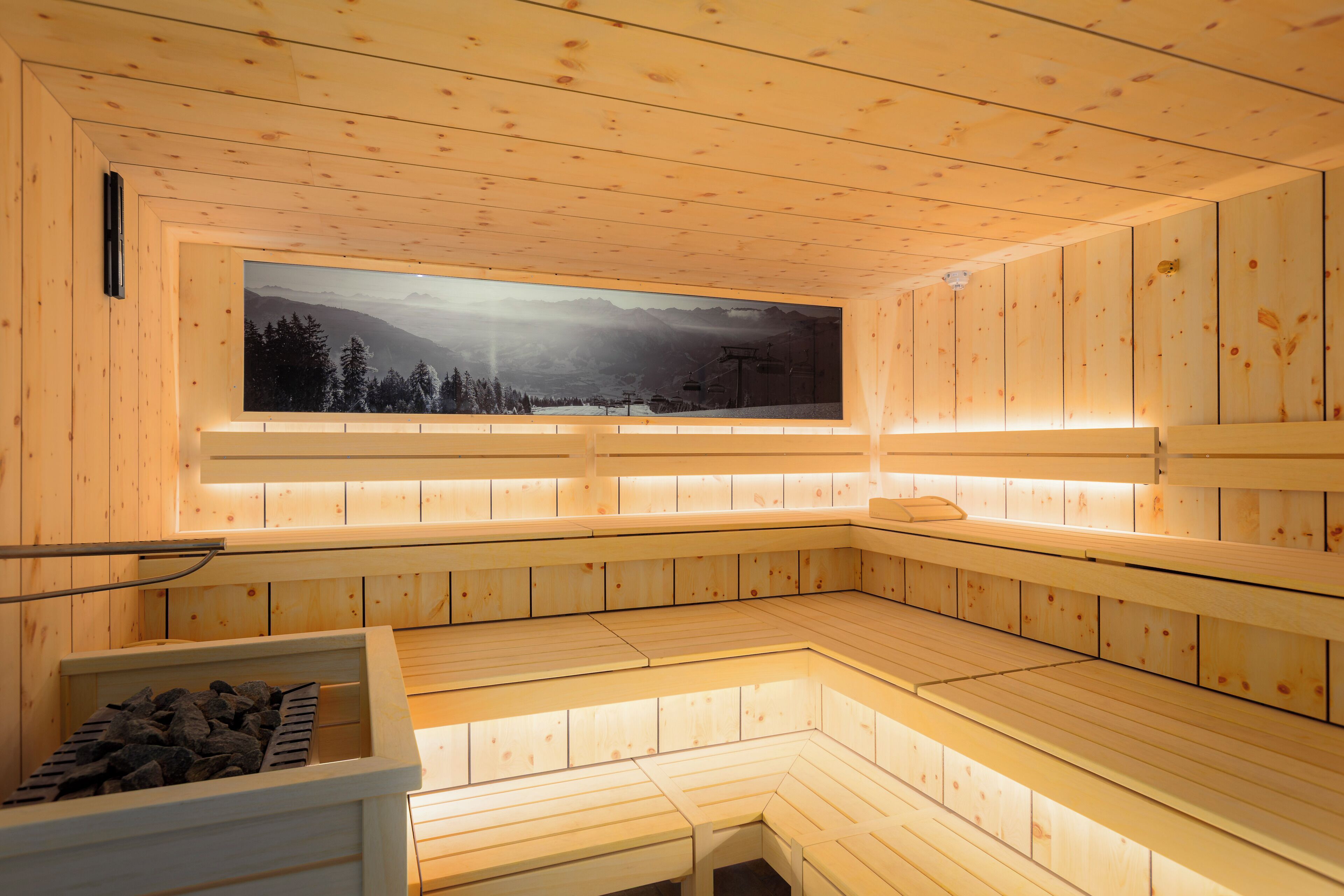 A sauna with wooden benches and a large window overlooking a snowy landscape.