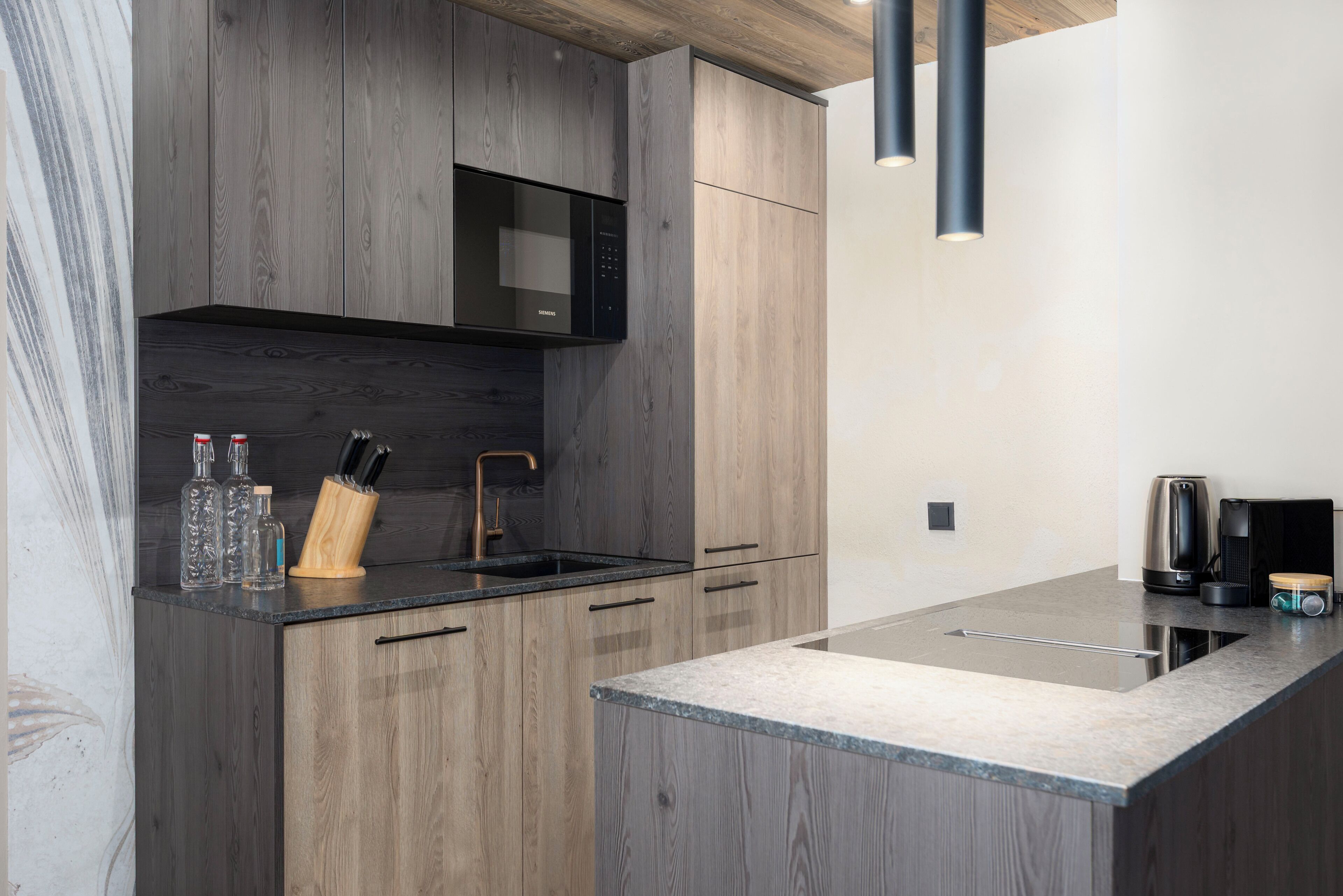 A modern kitchen with wood cabinetry, a built-in microwave, and a granite countertop.