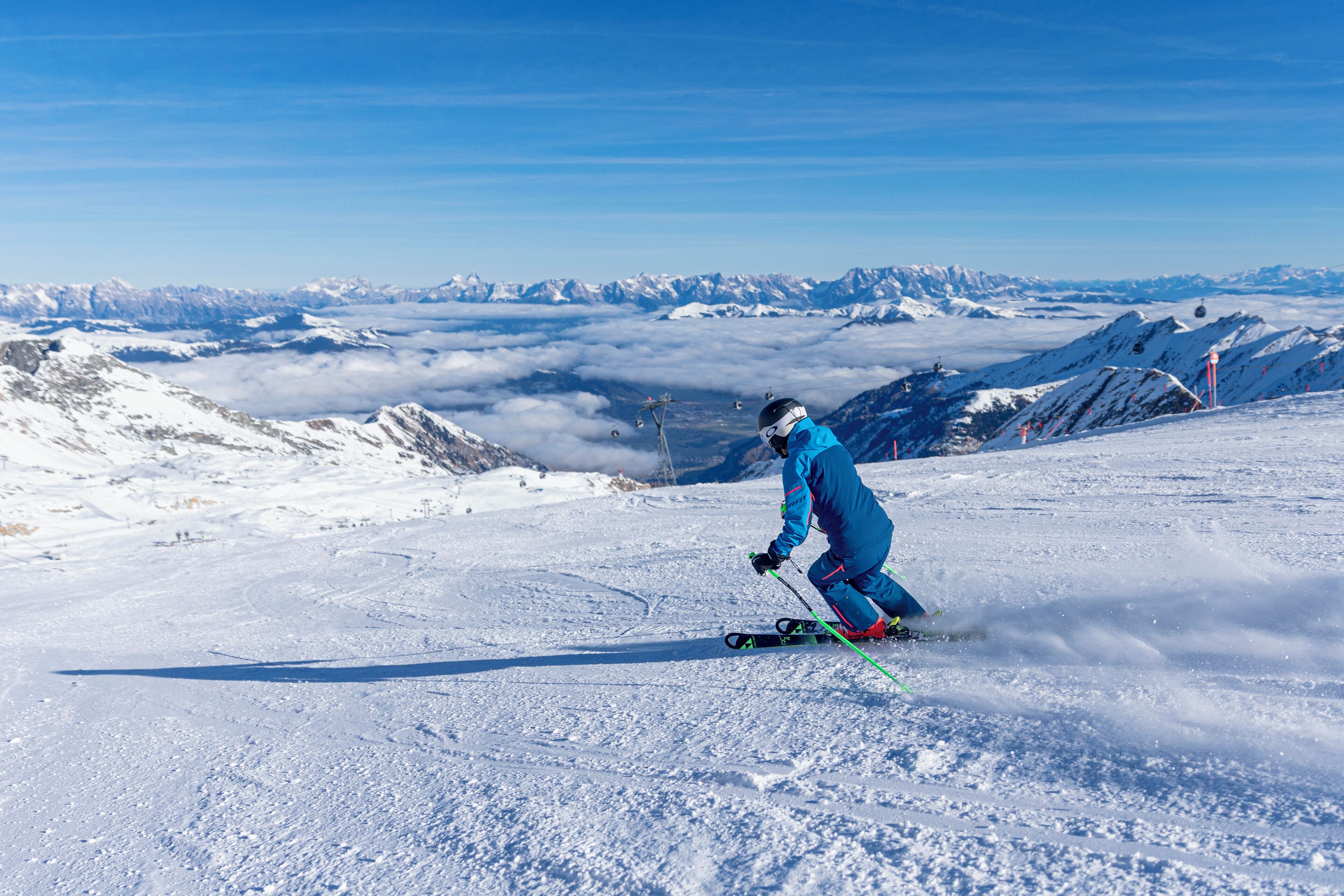 A skier on a snowy slope with a clear view of distant mountains and ski lifts.