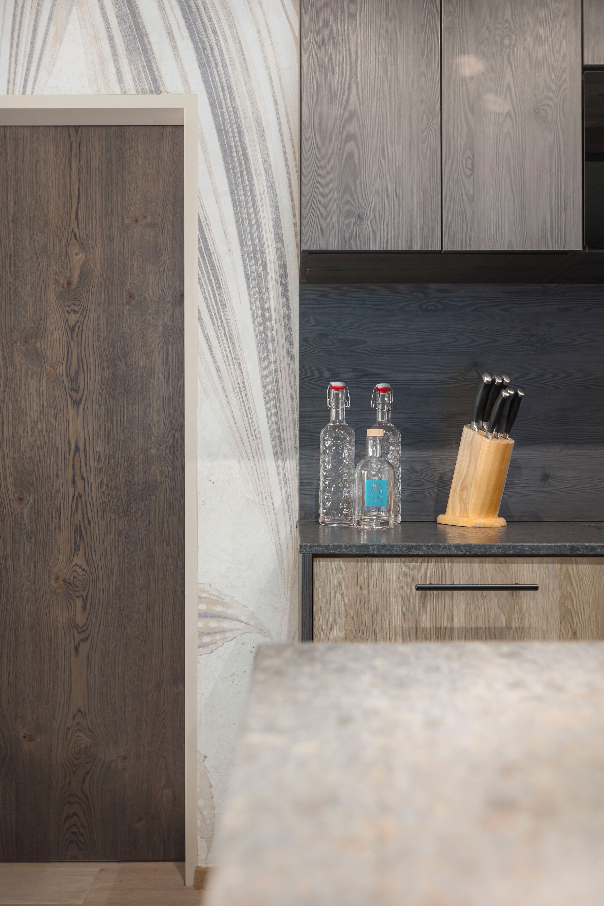 A kitchen with wooden cabinets, a marble countertop, and a knife block.