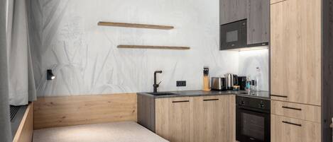Une cuisine compacte avec des meubles en bois, un four à micro-ondes encastré et un petit plan de travail.