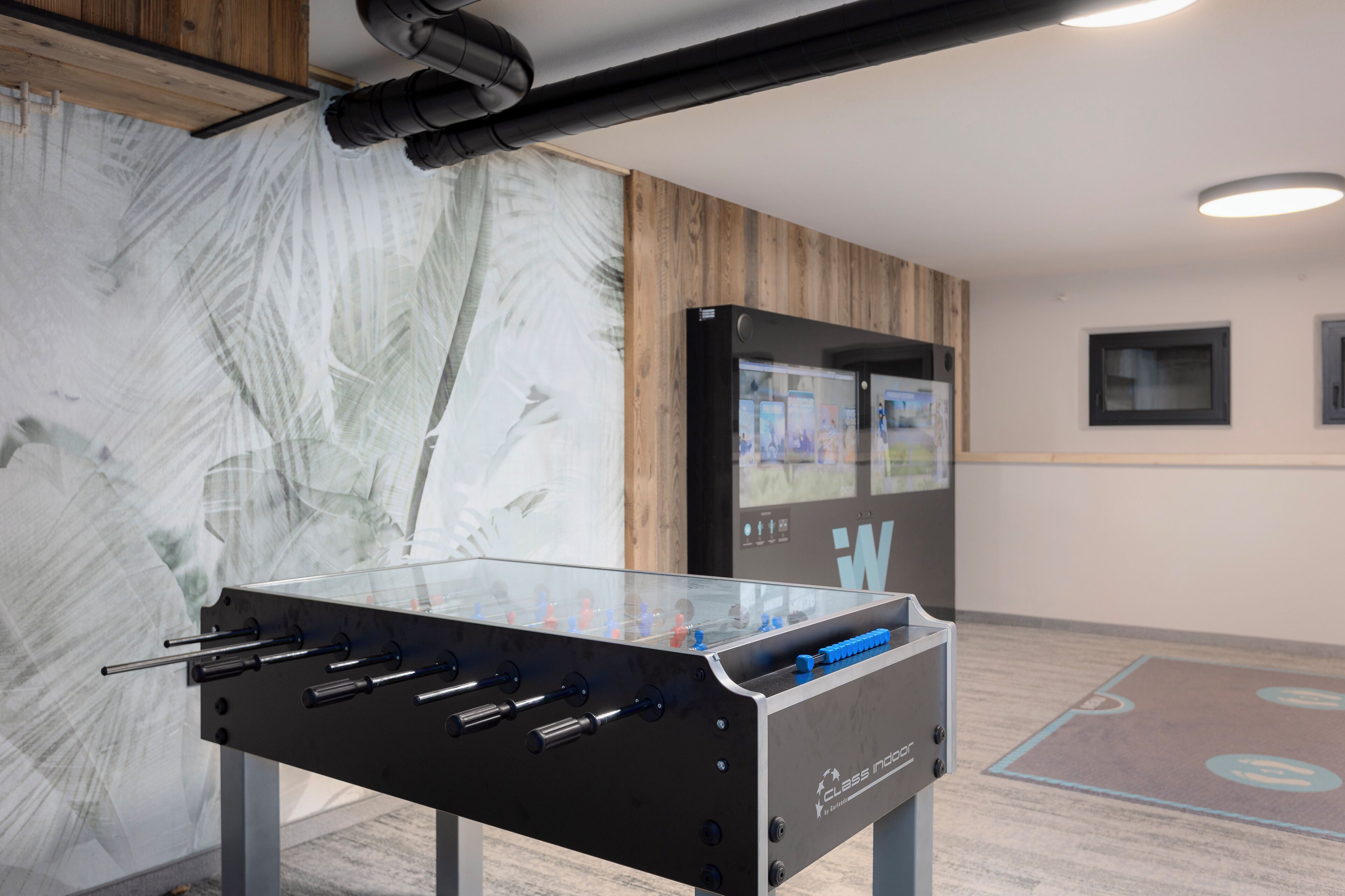 A foosball table in a room with wooden paneling and a large abstract painting.