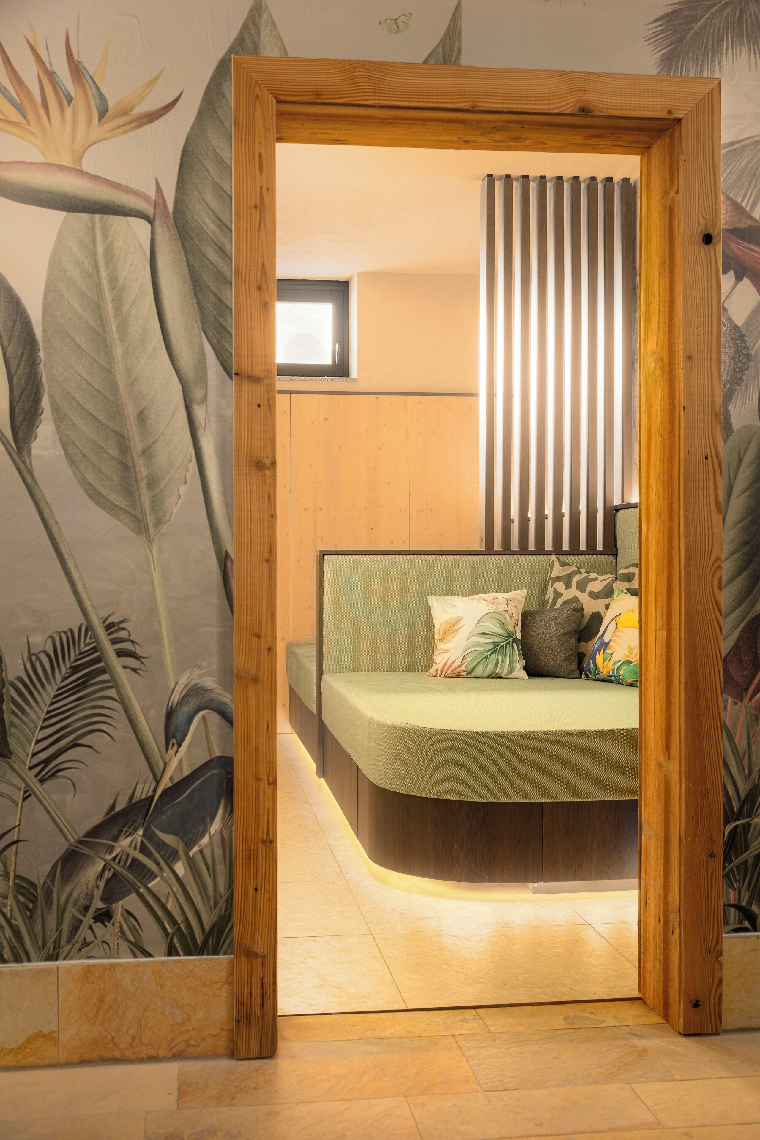 Une chambre à coucher avec un lit aux courbes originales, un cadre en bois et une fresque murale aux motifs tropicaux.