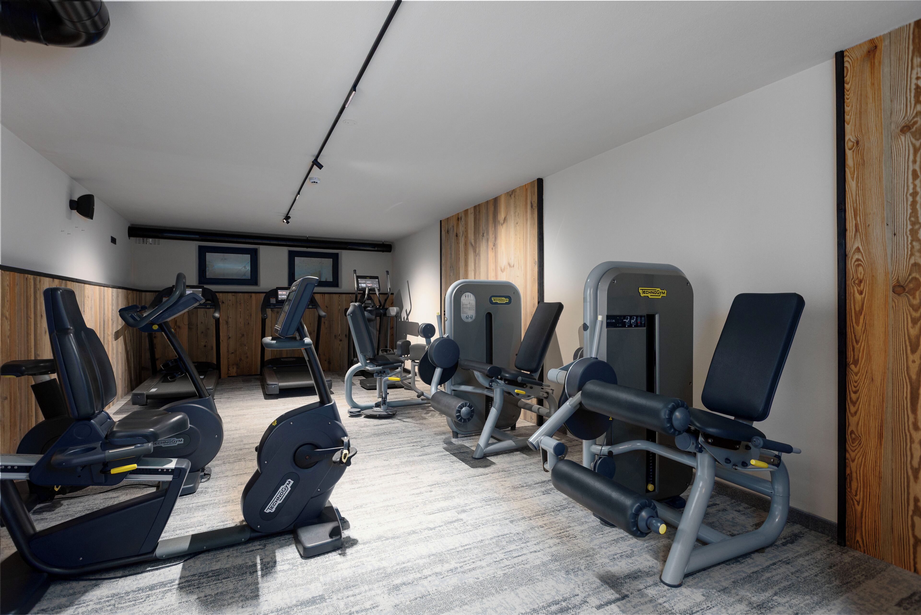 A gym with various exercise equipment including treadmills, elliptical machines, and weight machines.