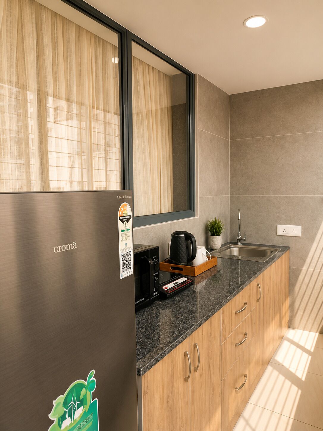 Una cocina moderna con un refrigerador de acero inoxidable, una cafetera y un lavamanos.