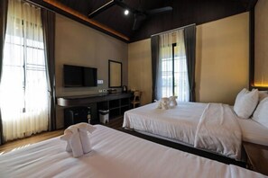 Una camera d'albergo con due letti, una scrivania con televisione e ampie finestre con tende.